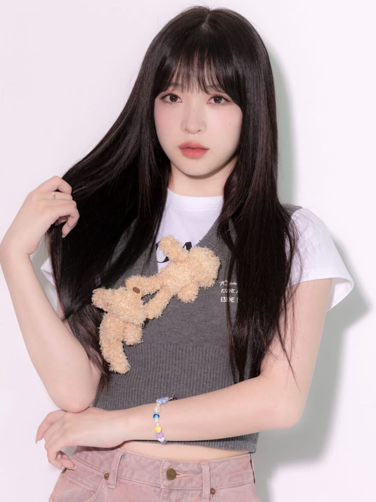 This may contain: a girl with long black hair and a teddy bear on her shoulder is posing for the camera